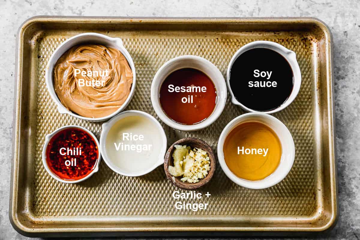 The ingredients you need to make homemade peanut sauce, including peanut butter, rice vinegar, sesame oil, soy sauce, honey, garlic and ginger.