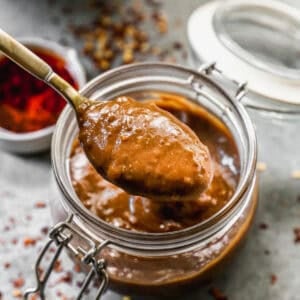 An easy Peanut Sauce recipe in a jar with a spoon lifting some up.