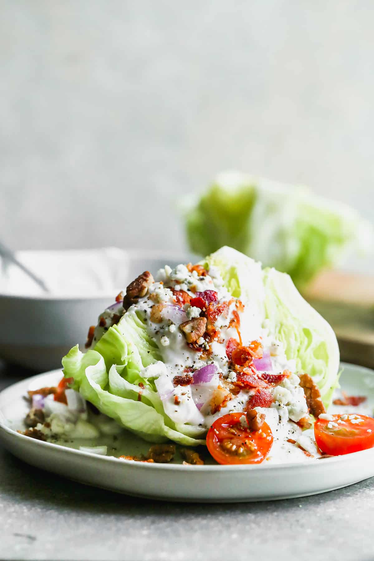 The best Wedge Salad recipe with a homemade blue cheese dressing and toppings on a plate, ready to enjoy. 