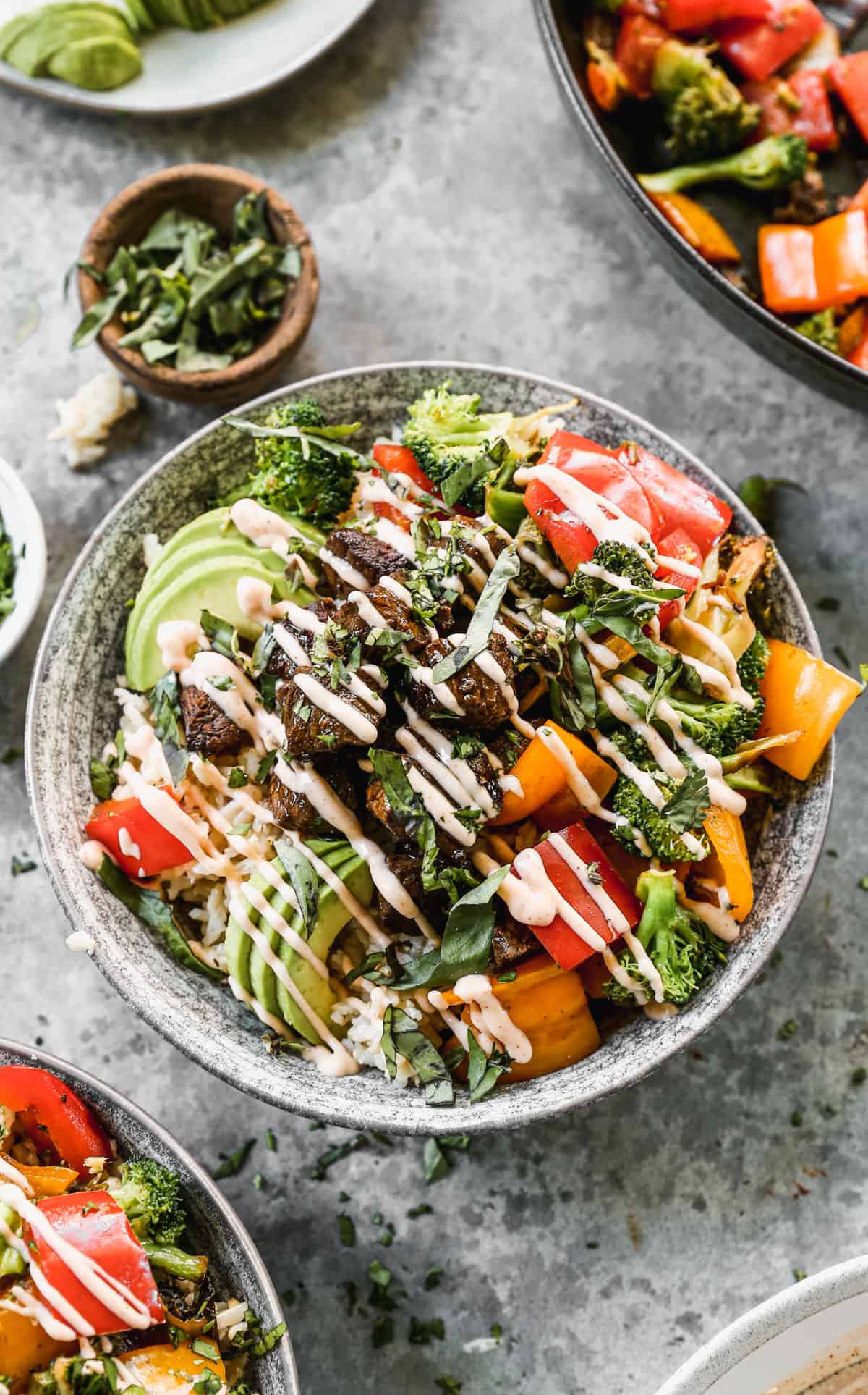 A Yum Yum Bowl recipe with a bed of rice topped with steak, bell peppers, broccoli, fresh avocado, and a drizzle of yum yum sauce.