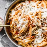 A homemade Baked Ziti recipe in a pan, with a spoonful being lifted.