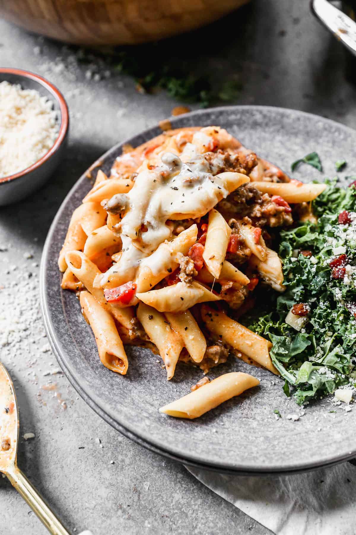 The best Baked Ziti recipe served on a plate next to a green kale salad. 