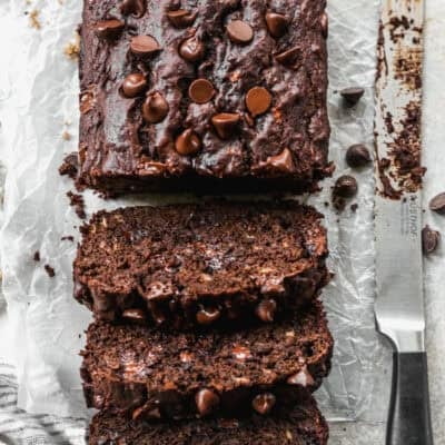 Moist chocolate banana bread baked in a loaf pan and sliced on parchment paper to reveal gooey melted chocolate chips inside.