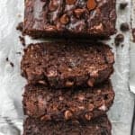 Moist chocolate banana bread baked in a loaf pan and sliced on parchment paper to reveal gooey melted chocolate chips inside.