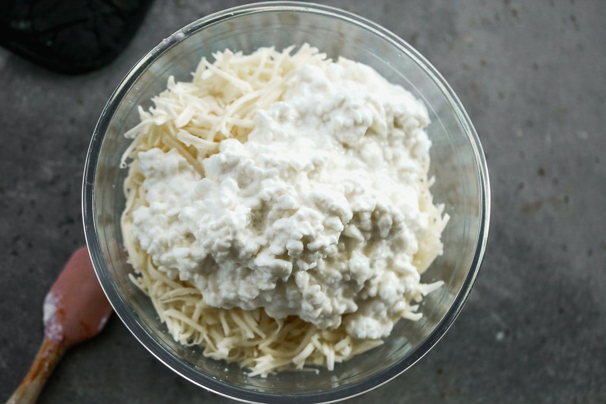 Mozzarella cheese, cottage cheese, and parmesan cheese in a glass bowl.