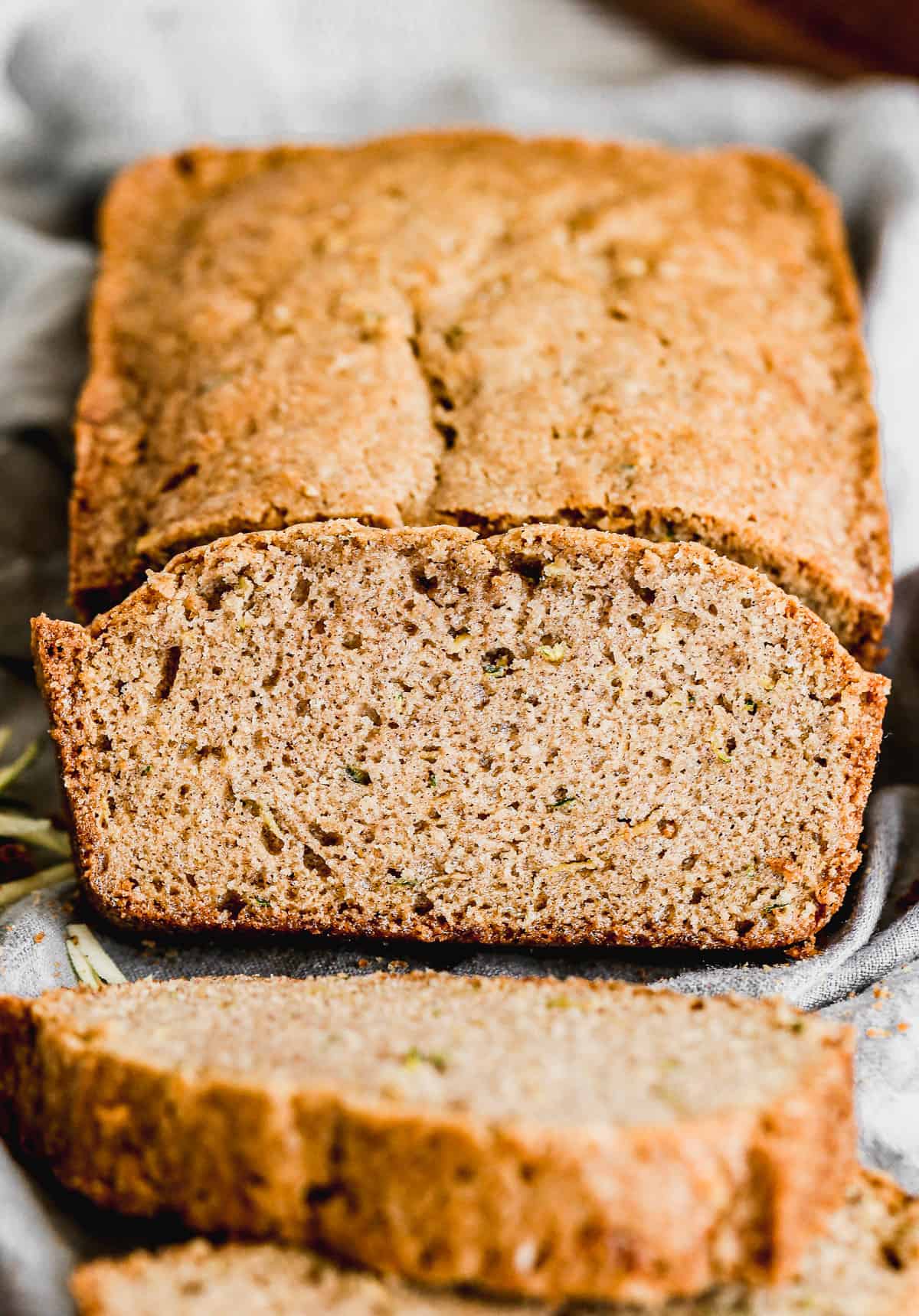 A slice of homemade zucchini bread with a slice cut from it.