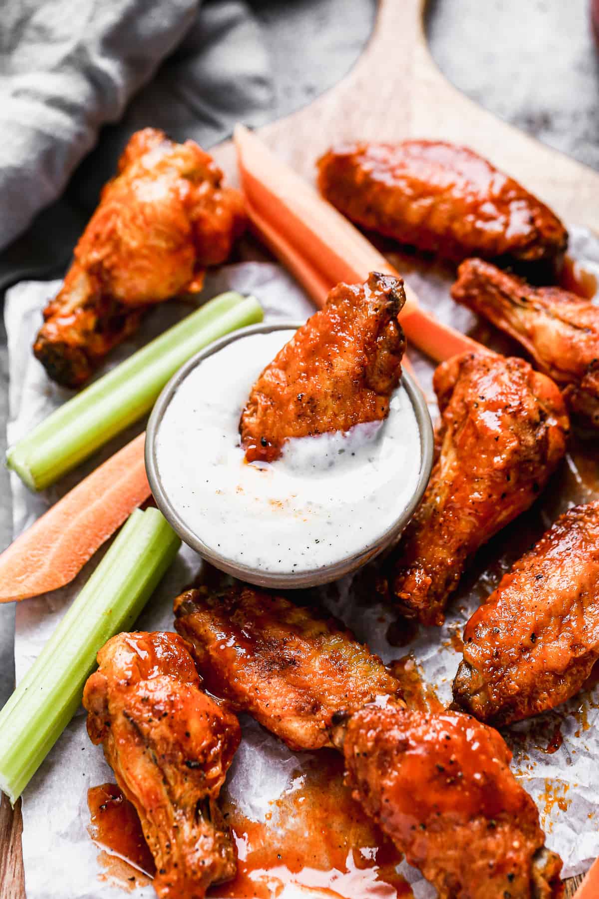 Air fryer ranch chicken wings on a platter with one wing being dipped in a cup of homemade ranch.