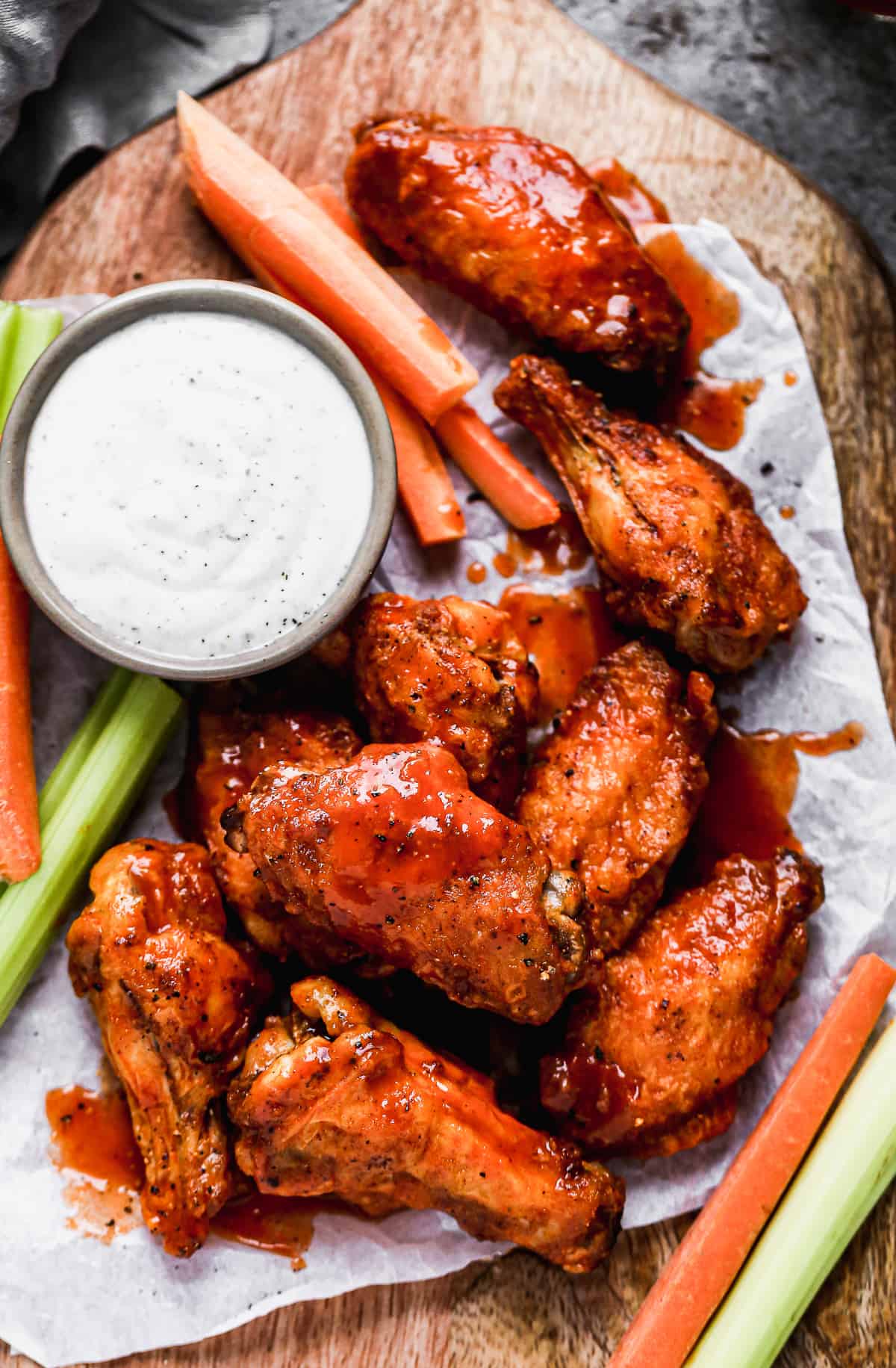 The best air fryer chicken wings on a wooden platter with carrots, celery, and a side of ranch.
