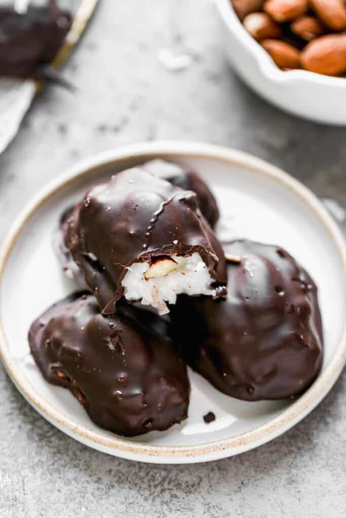 A homemade almond joy candy with a bite out of it, stacked on top of three more.