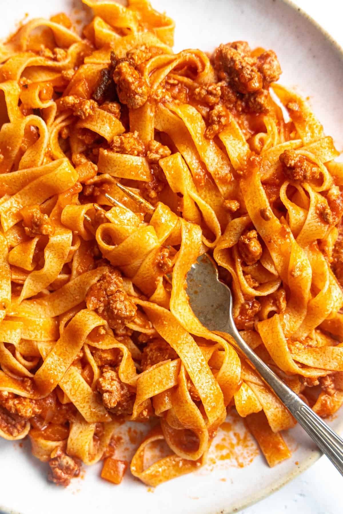 A close up image showing easy bolognese ragu being twirled with a fork.