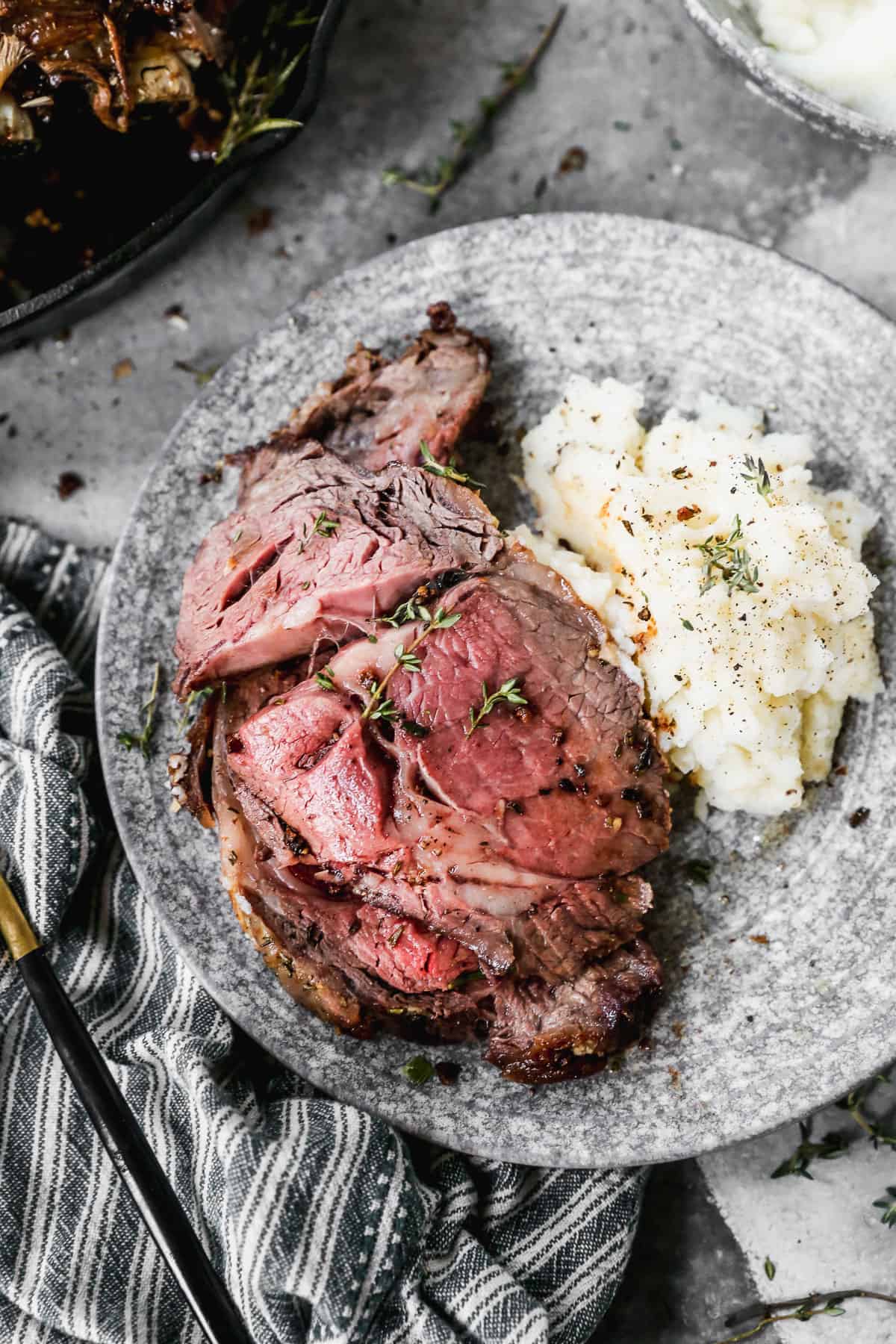 A slice of easy prime rib recipe on a plate with mashed potatoes.