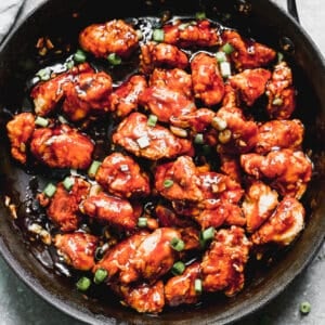 A pan with homemade General Tso's Chicken, garnished with chopped green onion.
