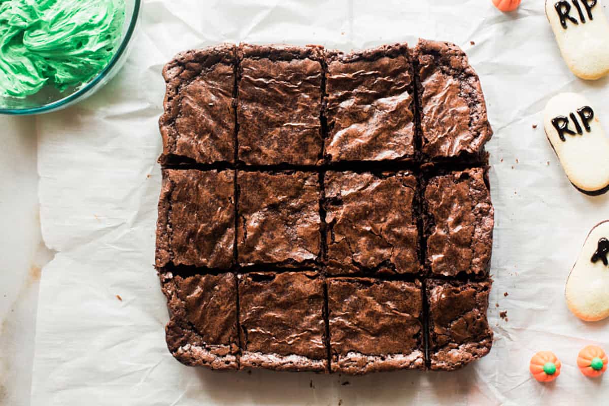 A square of freshly baked brownies on a piece of parchment paper,cut into squares.