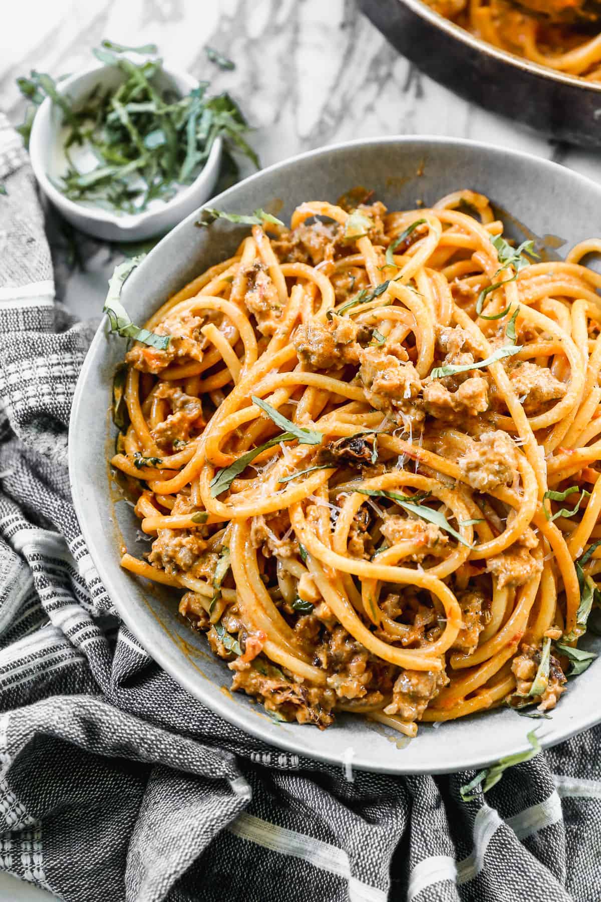 Harissa Pasta in a bowl topped with parmesan cheese and fresh basil.