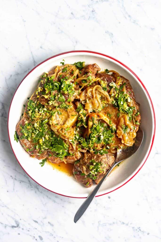 Italian Osso Buco recipe on a plate, garnished with gremolata on top.