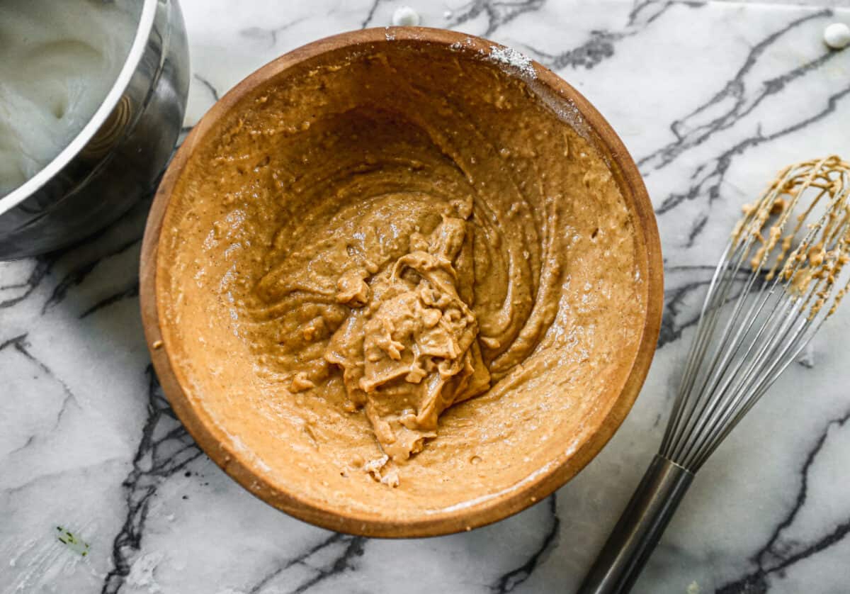 An easy pumpkin waffle batter in a brown bowl with a whisk next to it.