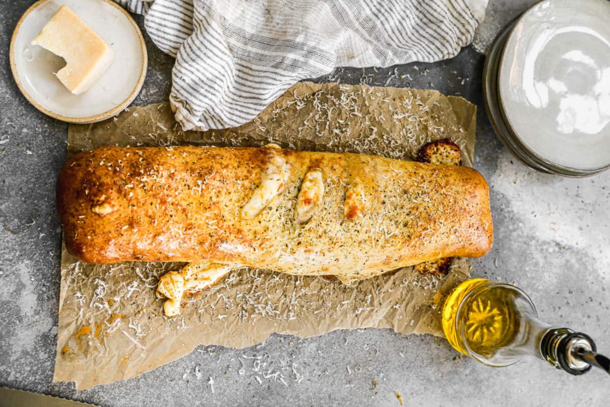 A baked stromboli topped with seasoning and parmesan cheese. 