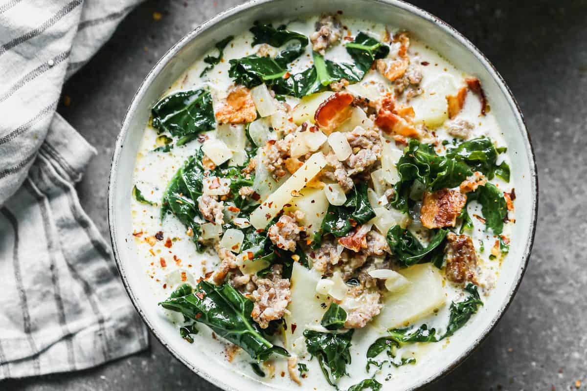 Save this creamy Zuppa Toscana recipe for a cozy homemade dinner. Italian sausage, potatoes, kale, bacon, and cream make a hearty soup with Olive Garden-inspired flavor. Includes stovetop, slow cooker, Instant Pot, and make-ahead instructions.
