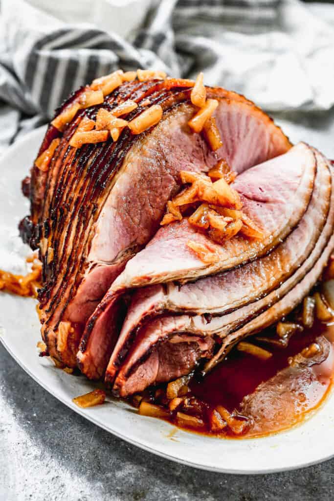A spiral baked ham with a pineapple brown sugar glaze poured on top, ready to serve.