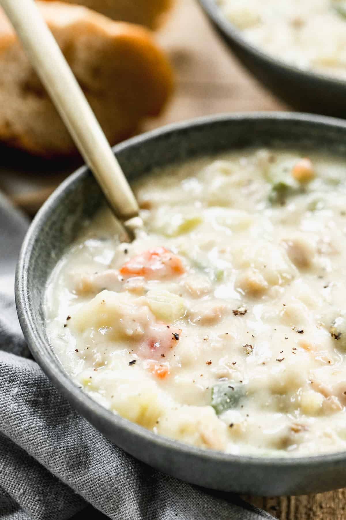 A close up image showing a bowl of easy Clam Chowder with a spoon in it.