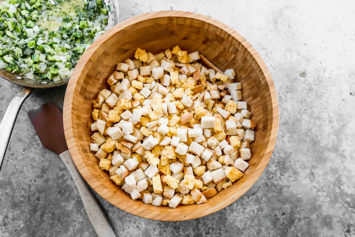 A wooden bowl filled with cornbread and white bread cubes, dried out for cornbread stuffing.