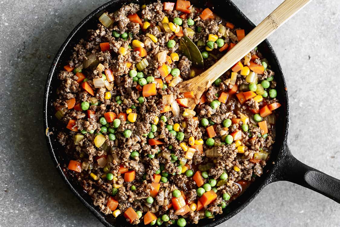 Ground beef, sausage, and vegetables being mixed together to make an easy shepherd's pie.