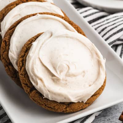 Soft and chewy ginger molasses cookies on a plate, leaning against each other.