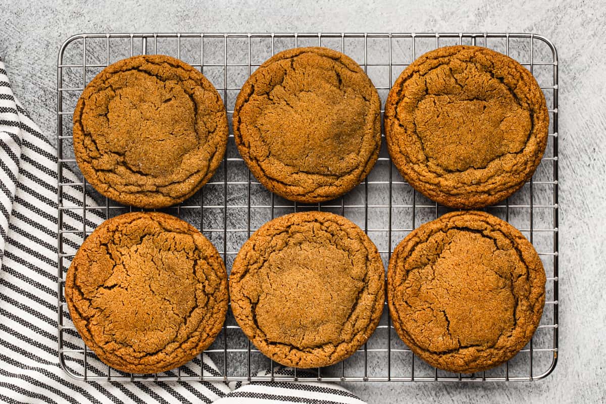 Six fresh ginger molasses cookies on a wire cooling rack.