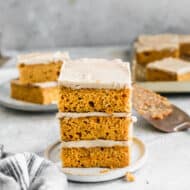 Three easy Pumpkin Bars with caramel frosting stacked on top of each other.