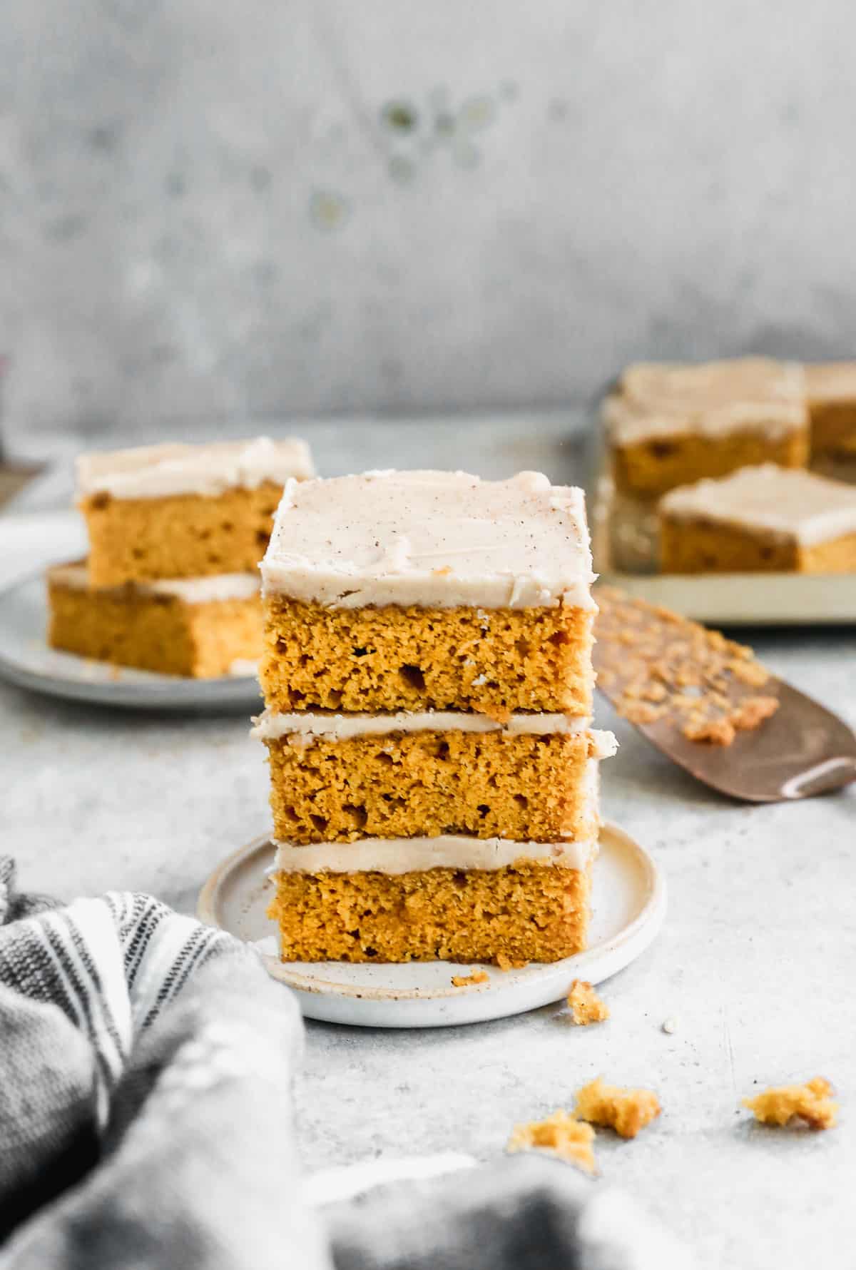 Three easy Pumpkin Bars with caramel frosting stacked on top of each other.