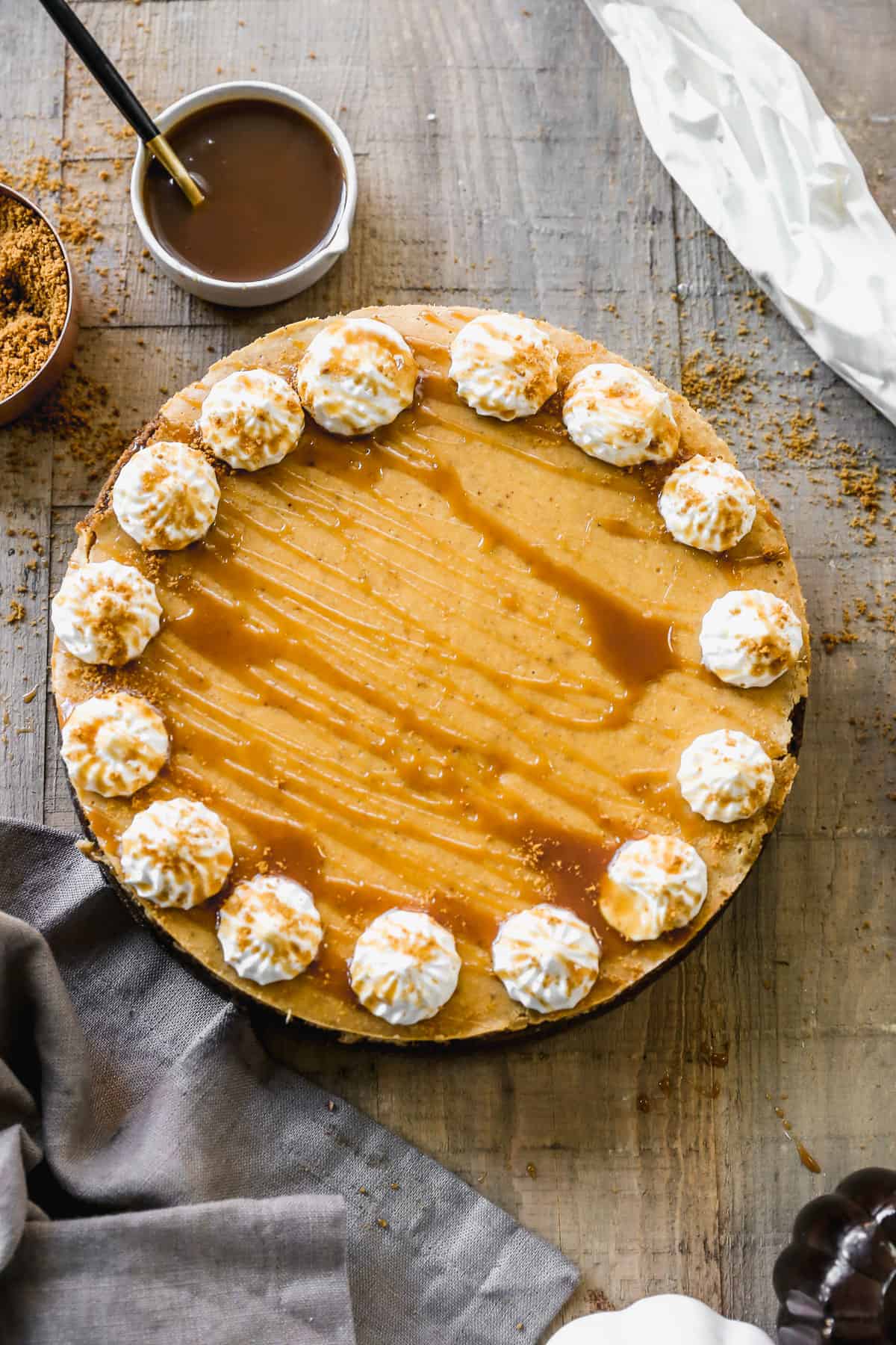 A homemade Pumpkin Cheesecake decorated with piped whipped cream and caramel sauce.