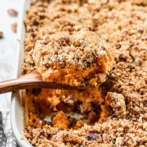 A piece of the best Sweet Potato Casserole recipe being lifted out of a rectangle pan to serve.