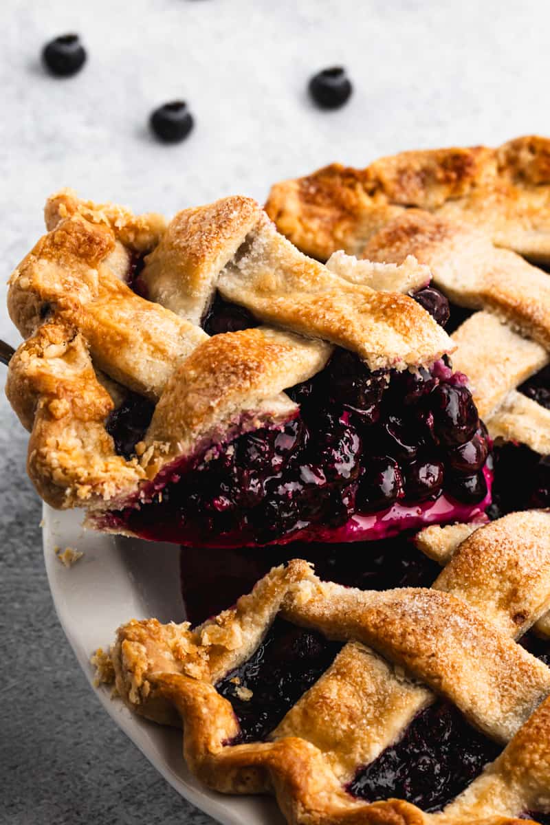 A slice of fresh Blueberry Pie, being lifted out of the pie dish.
