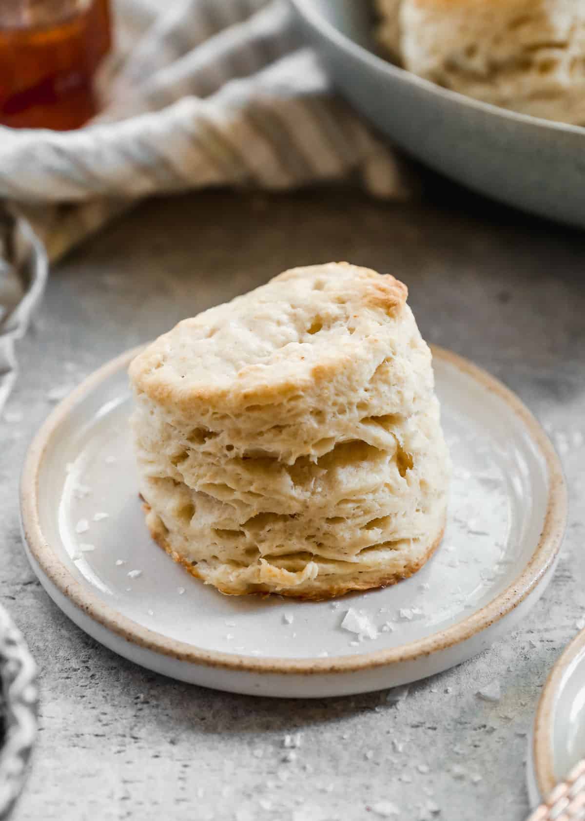 A flaky, homemade Buttermilk Biscuit on a small plate.