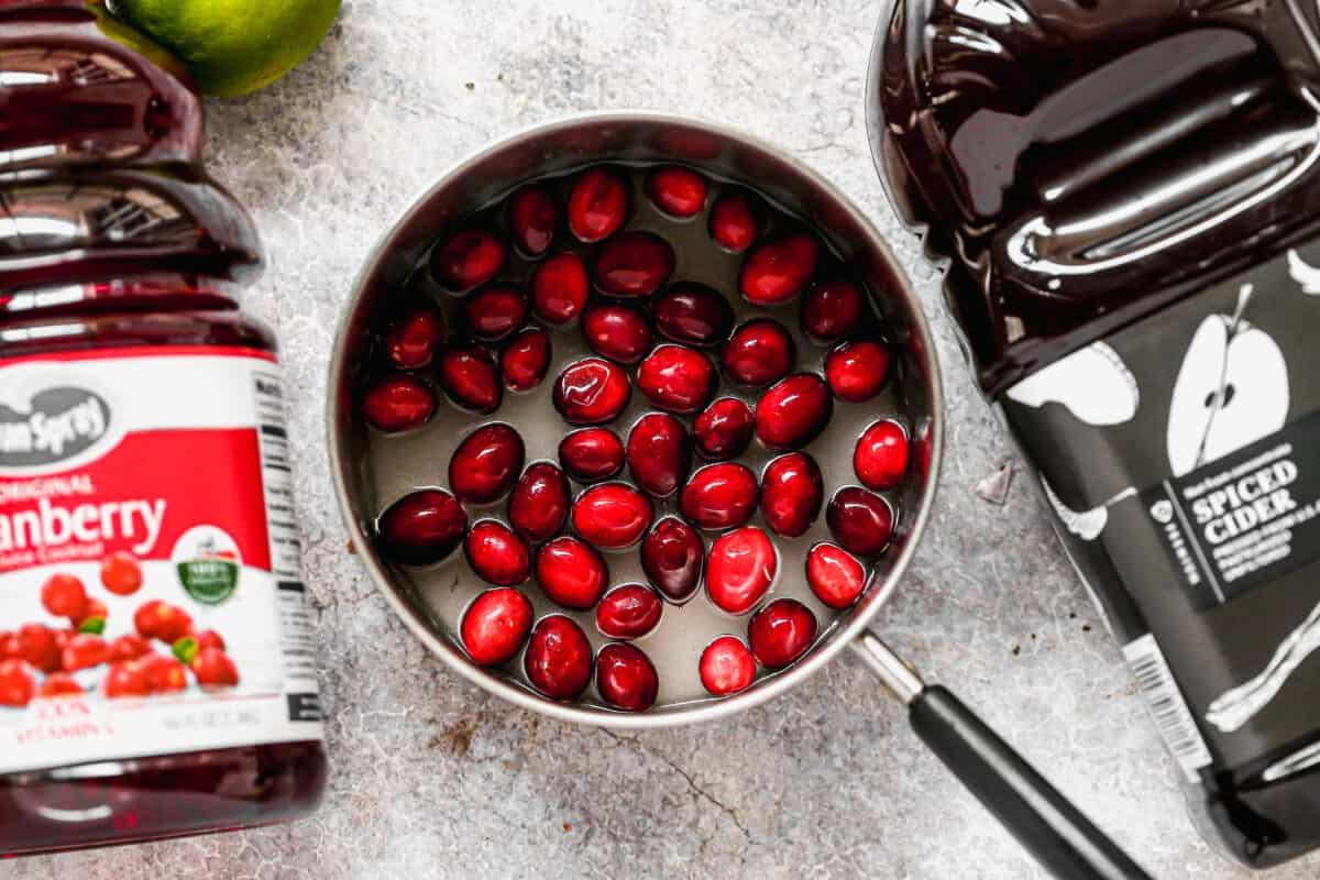 A saucepan with water, sugar, and cranberries to make the best Christmas Punch.