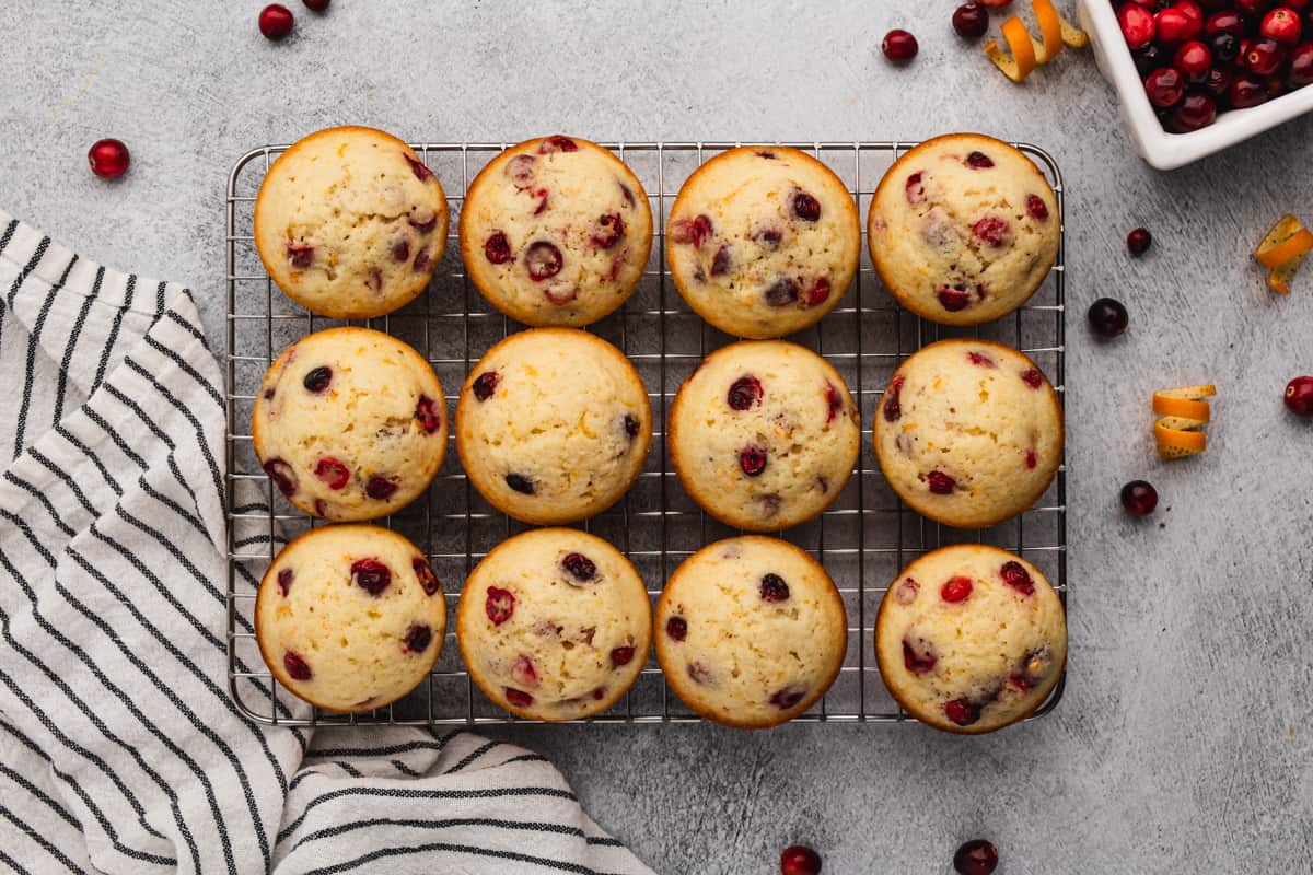 Twelve homemade Cranberry Orange Muffins on a wire cooling rack. 