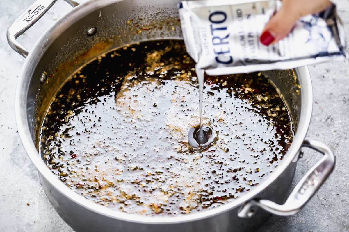 A package of certo liquid pectin being poured in a pot of the best pepper jelly to help it set up.