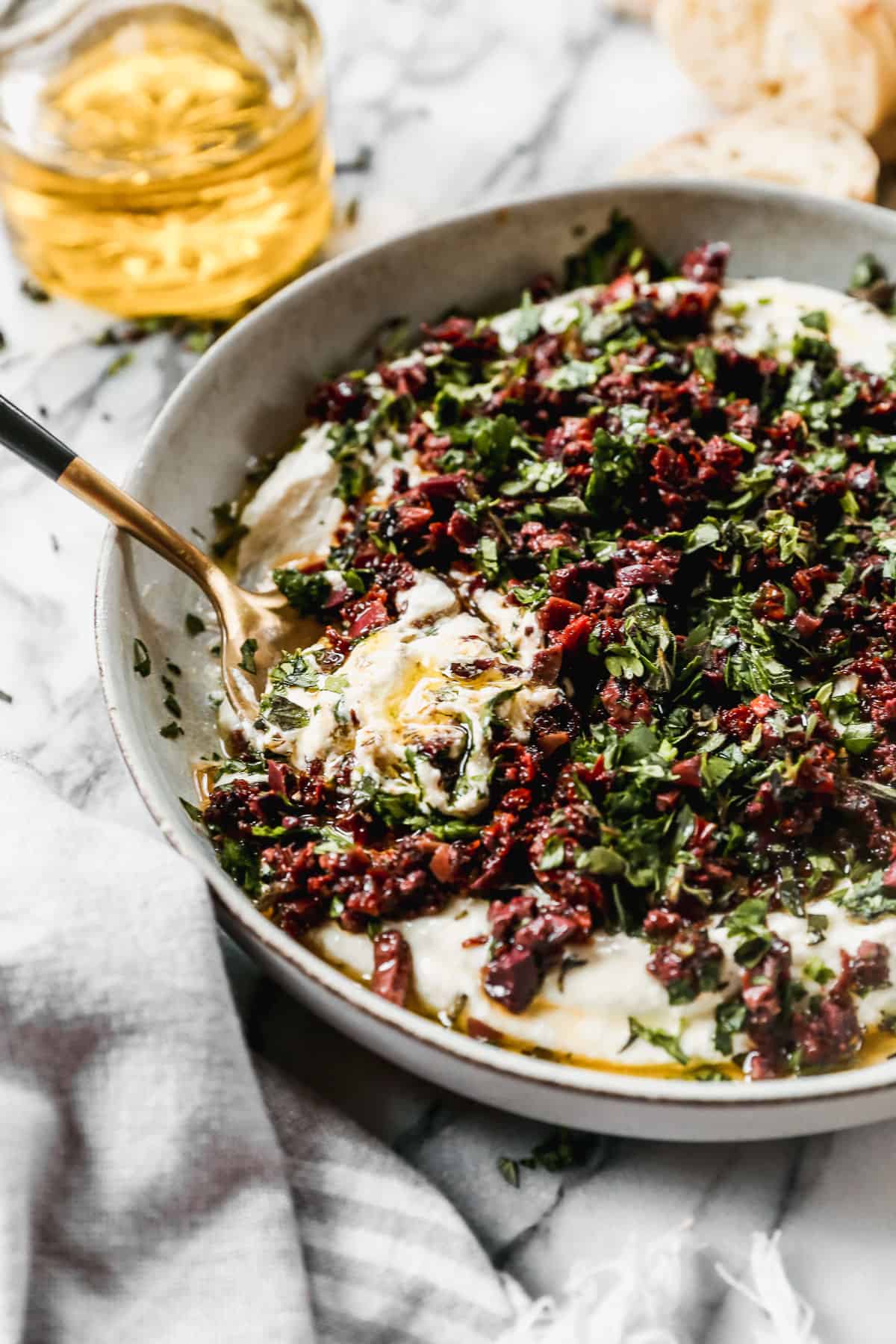 A Whipped Goat Cheese Dip, topped with chopped sun-dried tomatoes and herbs, ready to be served with crackers and pitas.