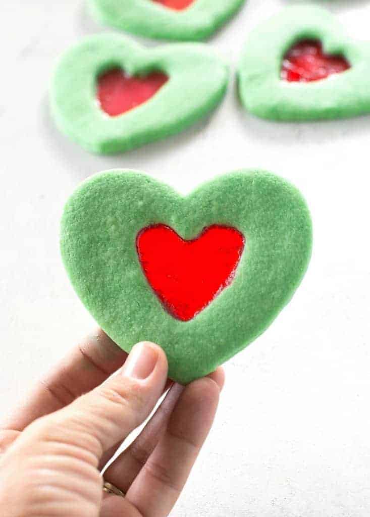 Grinch heart cookies, being held up by someone's hand.