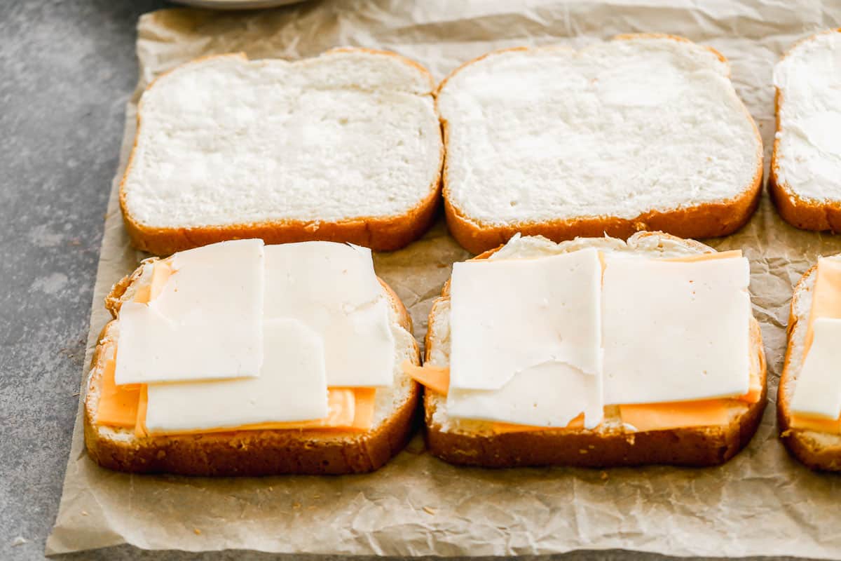 An image showing cheddar cheese and gruyere on top of thick white bread to make easy air fryer grilled cheese sandwiches.