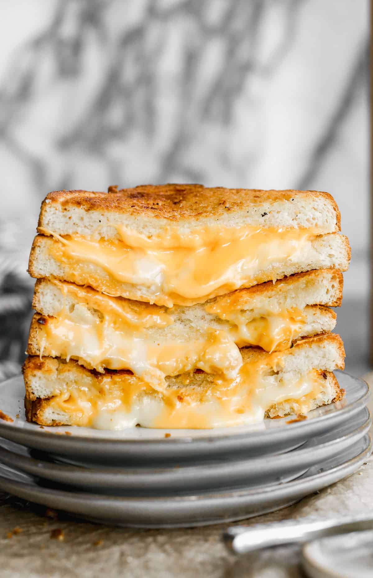 The best Air Fryer Grilled Cheese recipe cut in half and stacked on top of each other, showing the melted cheese. 