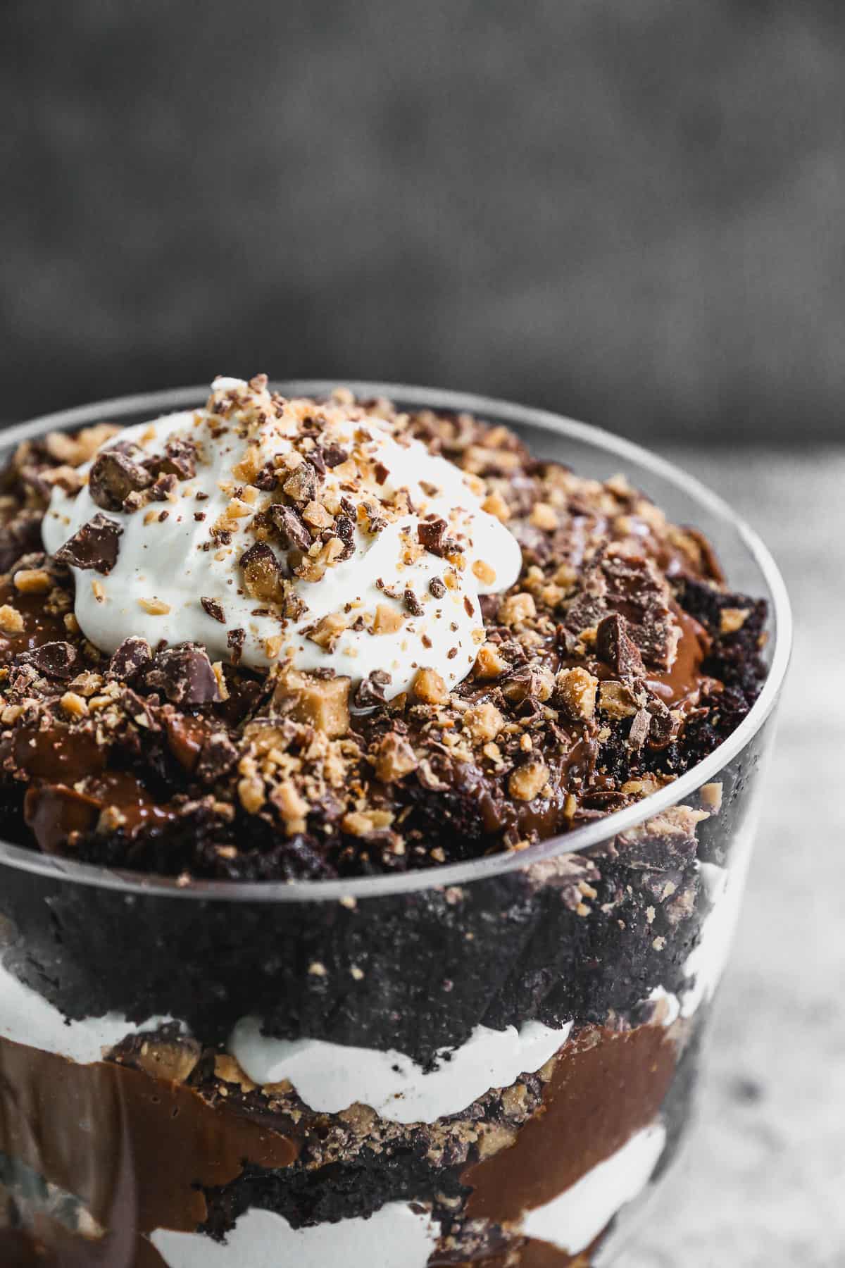 A close up image of a simple chocolate trifle recipe, topped with whipped cream and crushed heath bars.