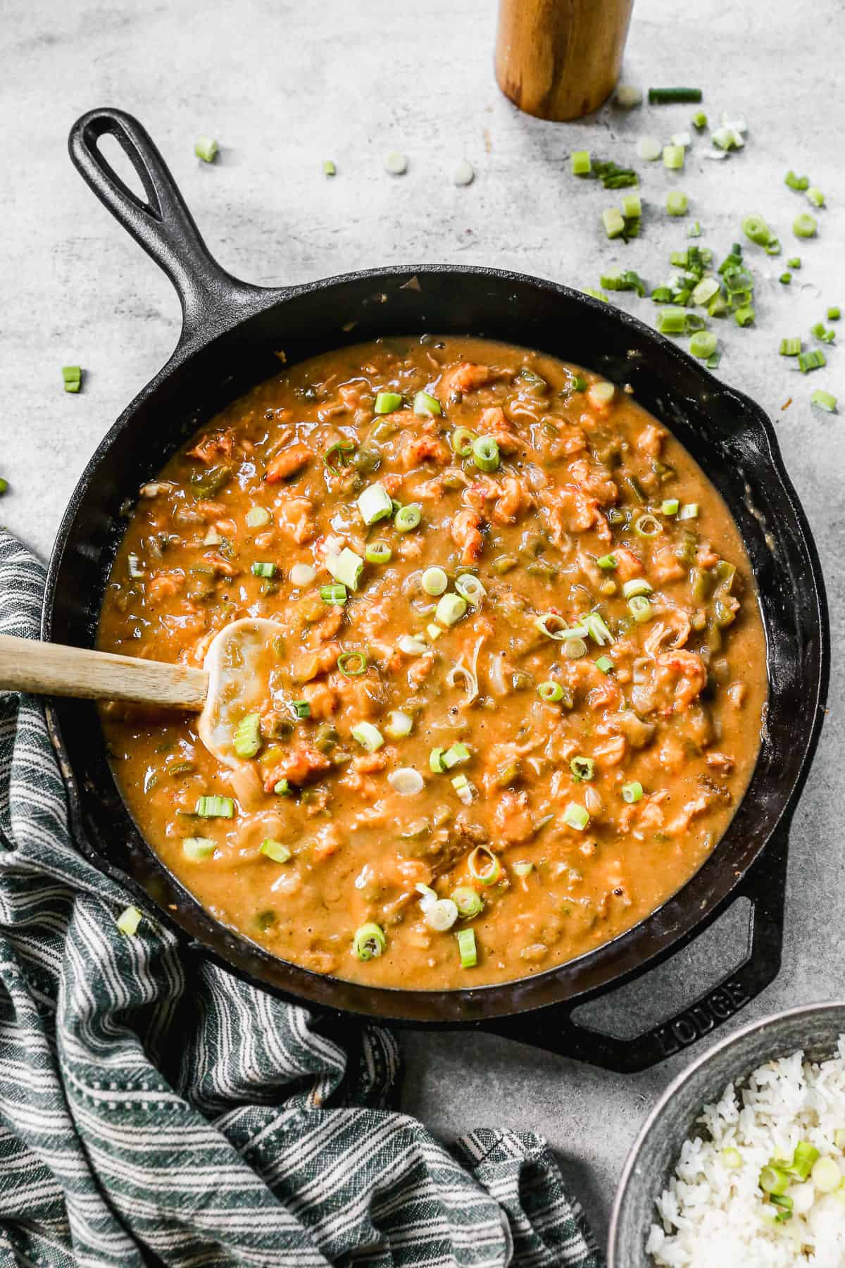 An easy Crawfish Etouffee recipe in a cast iron skillet, topped with green onions and ready to eat.