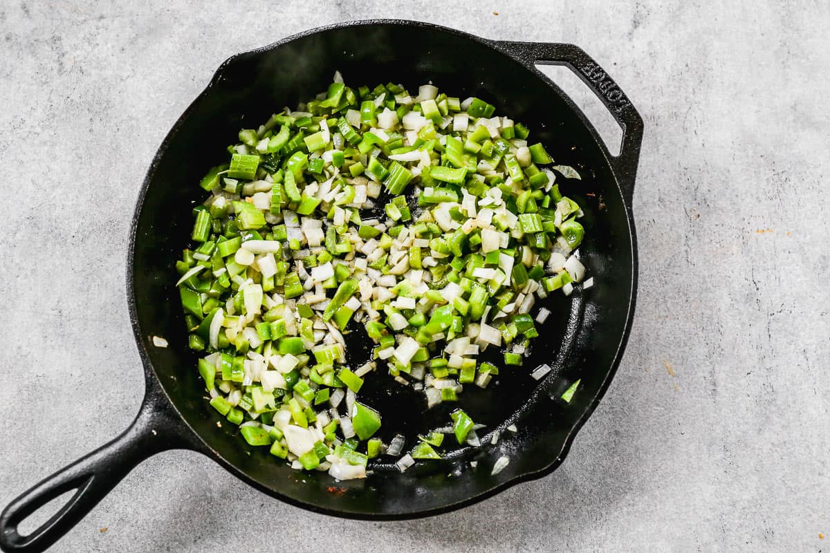 Chopped onions, celery, bell pepper, and garlic in a cast iron pan. 