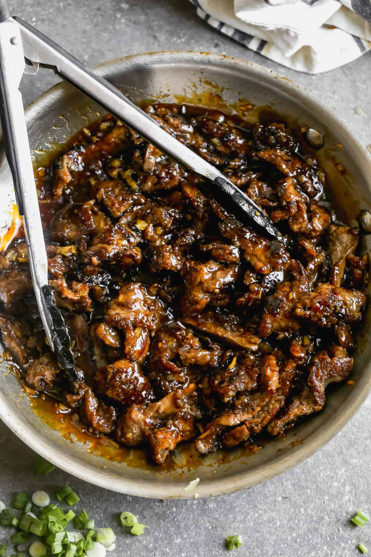 A PF Changs Mongolian Beef copycat recipe in a pan, tossed in a garlic ginger sauce.