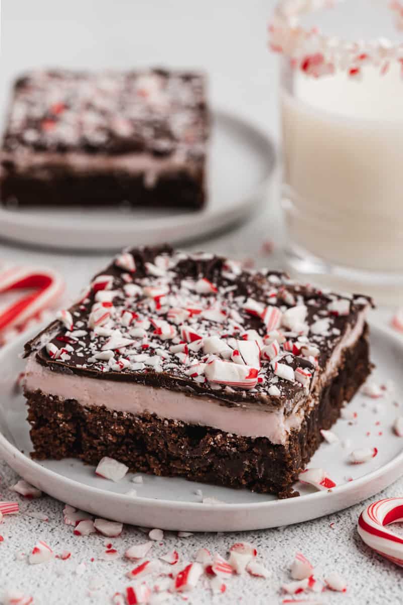 A square of homemade Peppermint Brownies on a white plate, topped with crushed candy canes.