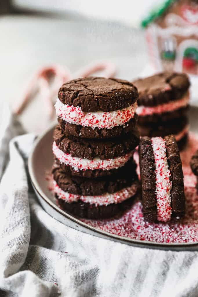 A stack of easy Peppermint Oreos with crushed candy canes around the edges of the frosting, ready to eat.