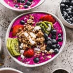 Easy Pitaya Bowls topped with homemade granola, strawberries, blueberries, kiwi, chia seeds, and shredded coconut.