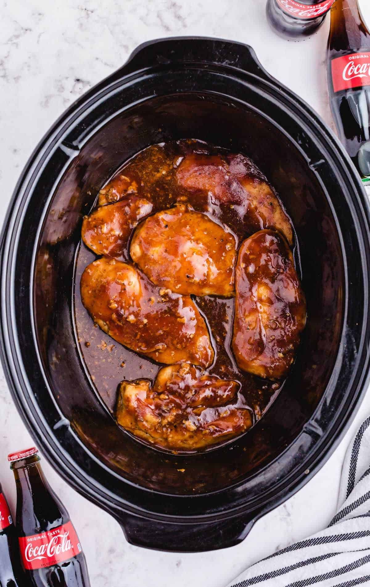 A crock pot filled with Coca Cola Chicken.