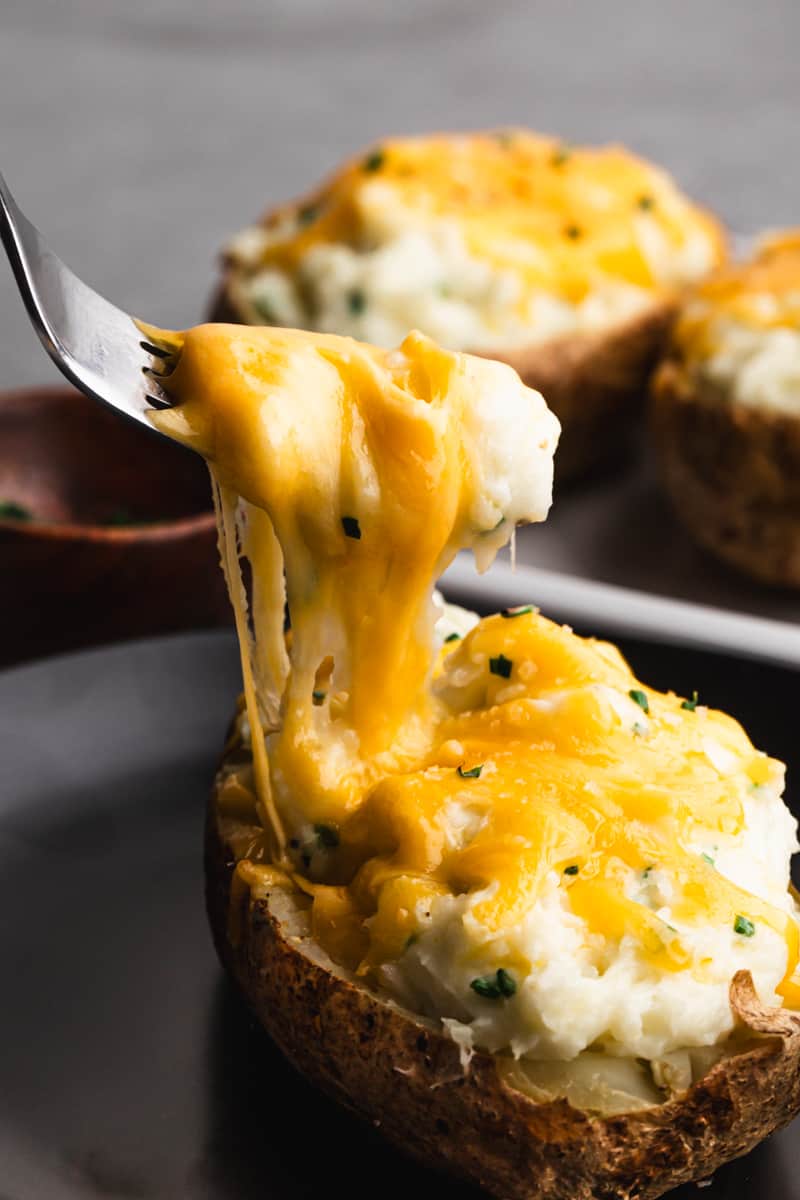 A fork lifting up a bite of a Twice Baked Potato, showing the melted cheese.